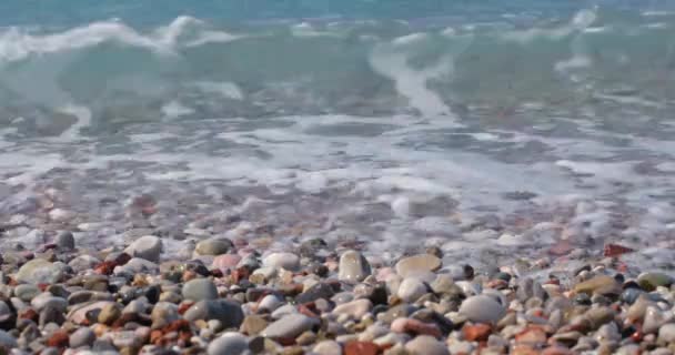海岸にビーチの小石と転がるターコイズブルーの海の波が飛び散る 美しい自然の背景 — ストック動画