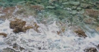 Turkuaz deniz dalgaları taşlı kıyıya sıçrayan, üst görünümü. Güzel doğal arka plan 4k