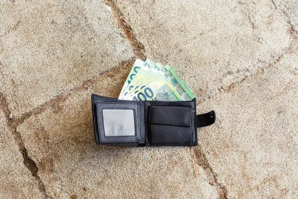Lost black leather wallet with money euro on street