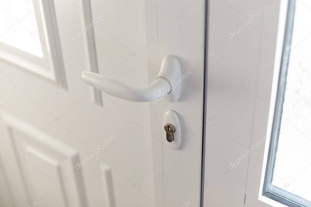 White plastic handle or doorknob and lock of house door