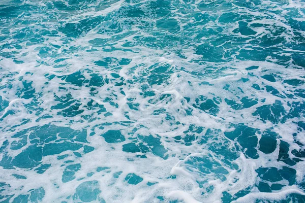 Бирюзовый фон на поверхности моря с брызгами волн — стоковое фото
