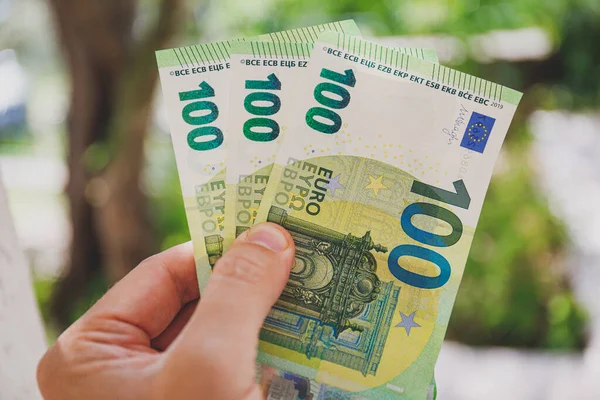 Мужская рука держит банкноты в 100 евро на зеленом фоне — стоковое фото