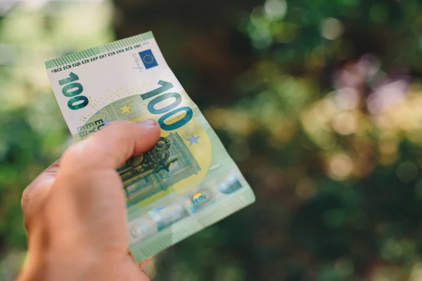 Mano masculina que sostiene el billete de 100 centésimas en euros sobre fondo verde — Foto de Stock