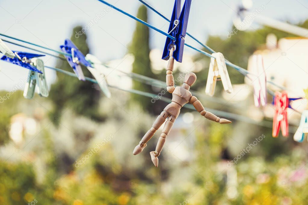 Wooden dummy puppet hanging with clothespin on clothesline