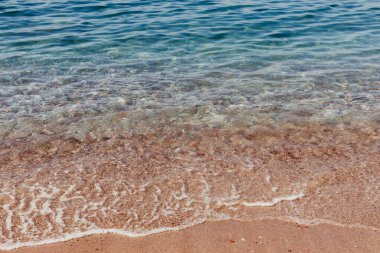 Turkuaz deniz dalgaları çakıl taşı kıyılarına vuruyor.