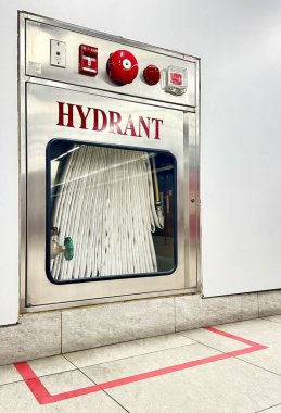 Duvarda beyaz hortum, hortum ve vana asılı yangın musluğu kutusu..