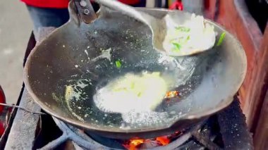 Geleneksel olarak yumurta ve sebzelerle haşlanmış erişte pişirme işlemi ve sokak satıcılarının büyük ateş alevleri..