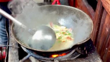 Geleneksel olarak yumurta ve sebzelerle haşlanmış erişte pişirme işlemi ve sokak satıcılarının büyük ateş alevleri..