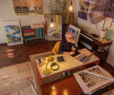 Orta yaşlı adam onun sanat stüdyosunda bilgisayar kullanarak ve onun tablet çizim