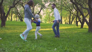 Bir aile. Anne, baba ve iki kızı çalıştırın ve bahar parkta blooming Bahçeleri eğlence.