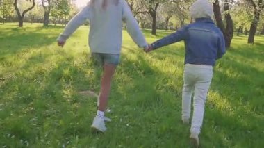 Çocuk park Blossoming orchard ile çalıştırın. steadicam park ve gülümseme çalıştırmak iki kız çekim. Ağır çekim