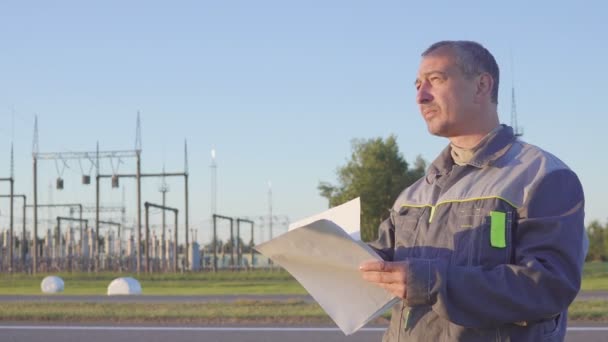 Trabajador en la Subestación Eléctrica. Trabajador con planos y portapapeles en reunión en subestación eléctrica . — Vídeos de Stock