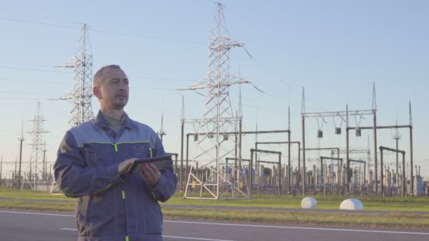 Inżynier i pracownik podstacji elektrycznych. Pracownik z tabletu i Schowka w posiedzeniu elektroenergetyczna. — Wideo stockowe