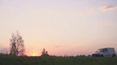 Bir araba bir alanda gün batımında silüeti. Yolun ve alan. Araba alanında.