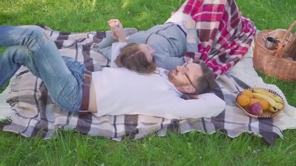 Föräldrar liggande i gräset - barnen har roligt och löpande bakgrunden i park — Stockvideo