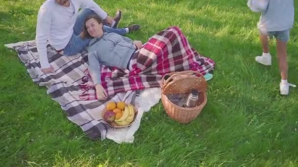A szülők feküdt a füvön - gyermekeknek szórakoztató és futás háttérben park — Stock videók