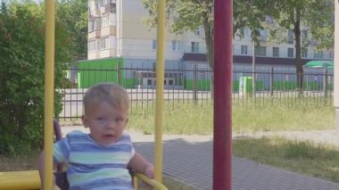 Şehrin arka planda bir salıncak üzerinde sürme bir 2 yaşındaki çocuk portresi. Ağır çekim