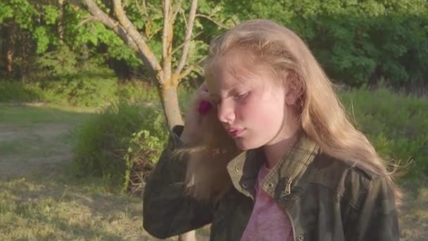 Ένδεκα ετών παλιά ξανθιά κοπέλα χτένες τα μαλλιά της στο ηλιοβασίλεμα — Αρχείο Βίντεο