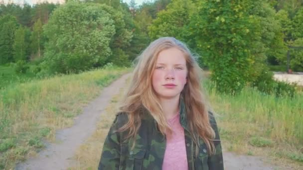 Una adolescente pasea por el bosque, disfrutando de la mañana en la naturaleza. El niño tiene el pelo rubio. Ella sonríe — Vídeos de Stock