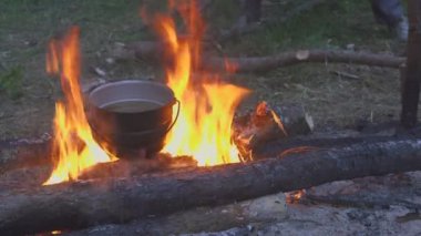 Kazan üzerinde akşam ormanda kamp ateşi ile pişirme
