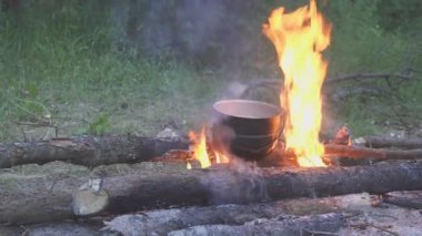 Kazan üzerinde akşam ormanda kamp ateşi ile pişirme