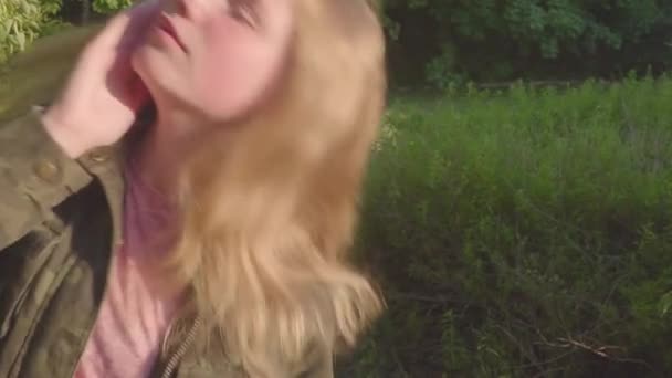 젊은 십 대 소녀는 그녀의 머리를 떨고, 머리와 재생 그리고 카메라 보고. 여름 공원 — 비디오
