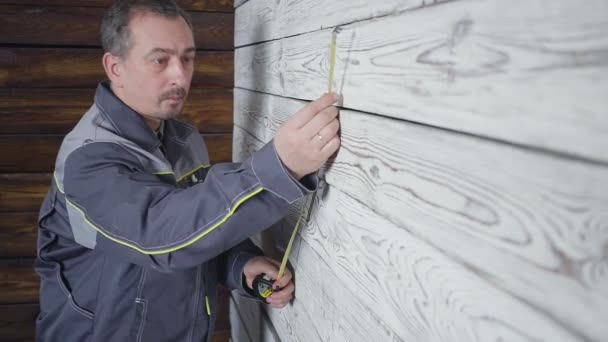 O trabalhador mede uma parede de madeira com uma régua — Vídeo de Stock