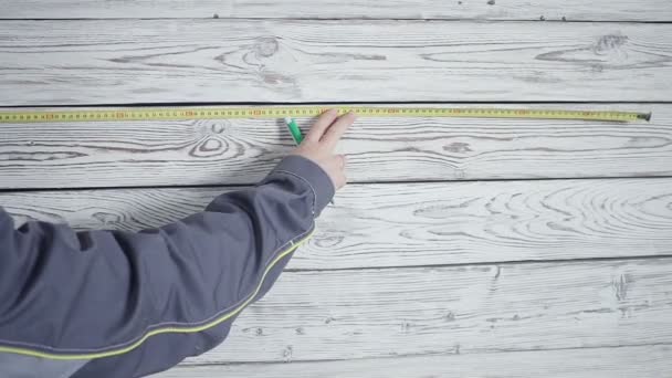 The worker measures a wooden wall with a ruler — Stock Video