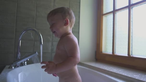 Zweijähriger Junge schwimmt und spielt im Badezimmer und lächelt schön. — Stockvideo