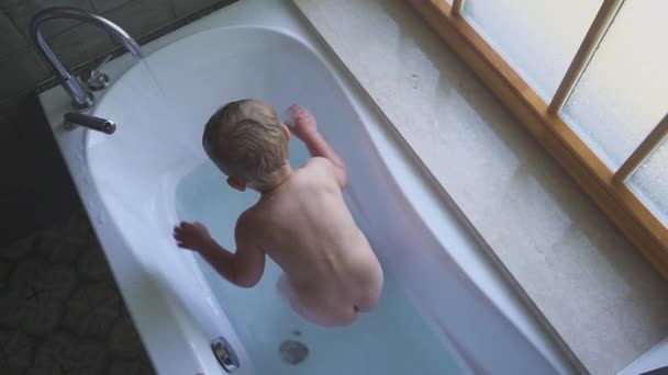 Lyckligt leende pojke simmar och leker i badrummet. — Stockvideo