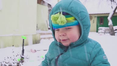 Bir yıl yaşlı erkek çocuk kar bahçede oynuyor.
