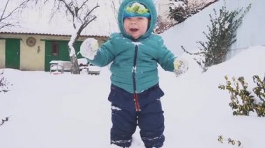 Bir yıl yaşlı erkek çocuk kar bahçede oynuyor.