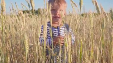Sahada ayakta mutlu iki yaşında bir çocuk ve onun elini dalgalar. ağır çekim. kavram. Küçük çiftçi.