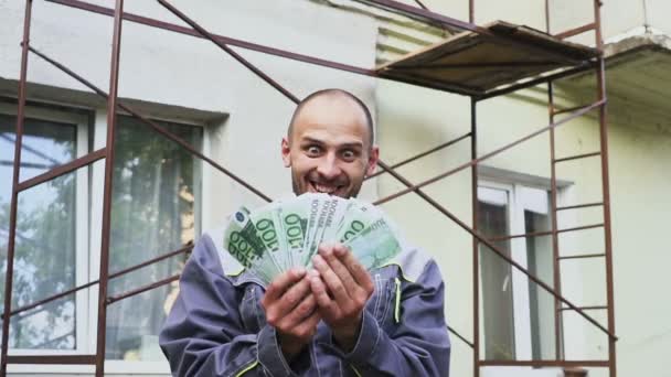 Feliz constructor emocional con un montón de dinero en euros al aire libre . — Vídeos de Stock