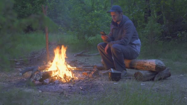 Männlicher Reisender isst am Abend bei Feuer aus Topf — Stockvideo