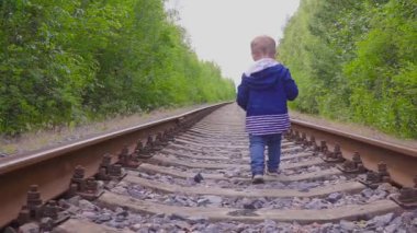 Demiryolu üzerinde yürüyen çocuk. Tehlikeli Oyunlar ve eğlence. Yaz günü.