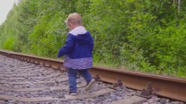 Demiryolu üzerinde yürüyen çocuk. Tehlikeli Oyunlar ve eğlence. Yaz günü.