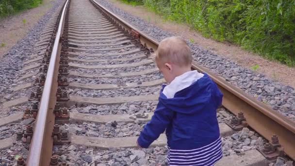 Un chico caminando en el ferrocarril. Juegos peligrosos y entretenimiento. Día de verano . — Vídeos de Stock