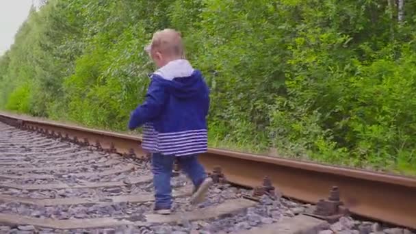 Un chico caminando en el ferrocarril. Juegos peligrosos y entretenimiento. Día de verano . — Vídeo de stock