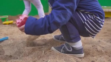 Kum havuzunda kazma bebeğim. Gülümsüyor ve kum dokunur.