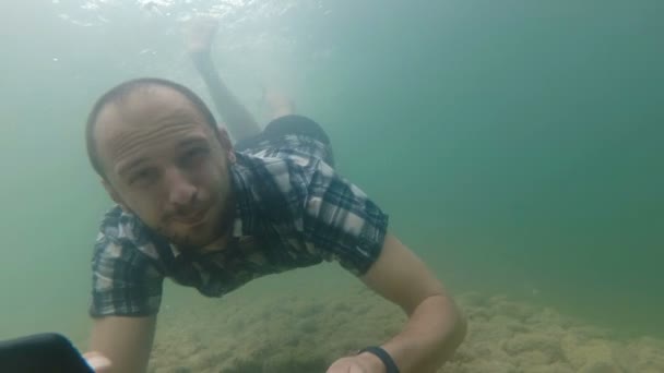 Ελεύθερος επαγγελματίας χρησιμοποιεί ένα smartphone, ενώ κατάδυση υποβρύχιο σε αργή κίνηση. Φυσική λίμνη — Αρχείο Βίντεο