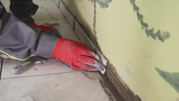 Trabalhador define pequenas telhas na parede na cozinha. As mãos dele estão a colocar a telha no adesivo. stedikam tiro — Vídeo de Stock