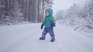 Küçük çocuk yürür ve karlı Wood, kış orman yavaş hareket üzerinde yürüyen çocuk oyun