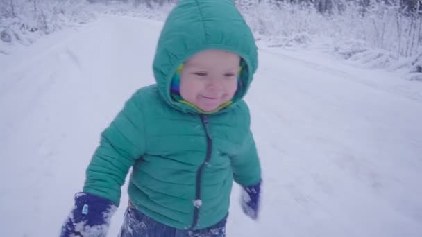 Menino caminha e brincando em madeira nevada, criança andando na floresta de inverno câmera lenta — Vídeo de Stock