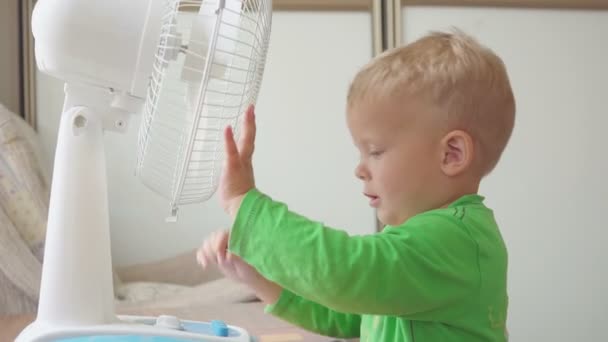 Infância, conceito de casa - menino bonito com grande ventilador de refrigeração — Vídeo de Stock