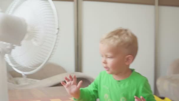 Childhood, home concept - cute little boy with big cooling fan — Stock Video