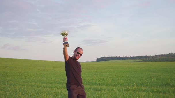 Vítěz s odměnou v jeho rukou zvedá ruce, má úspěch. On skočí a tance — Stock video