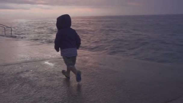 Niño feliz divertirse en la playa del mar. El chico juega en el océano. Chico corriendo en la orilla del mar. vacaciones con el niño. Agua divertida. Vacaciones familiares . — Vídeo de stock