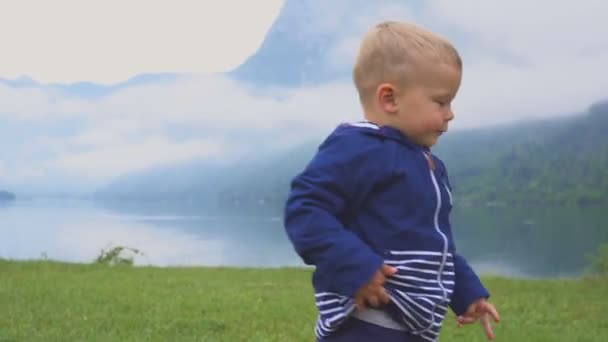 The little boy walks near the mountain lake. Running and frolicking in nature. — Stock Video