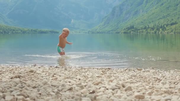 Orman dağ gölü su içindeki küçük çocuk 2 yıl. Arkadan görüntülemek. — Stok video
